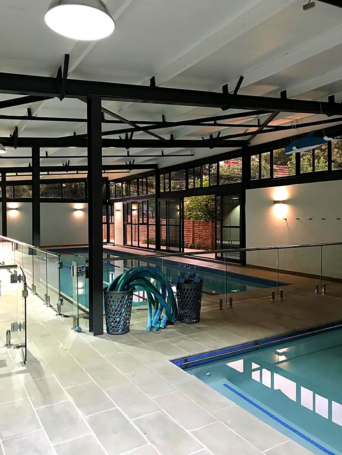 Indoor pool area in the evening with poolside equipment and warm lighting