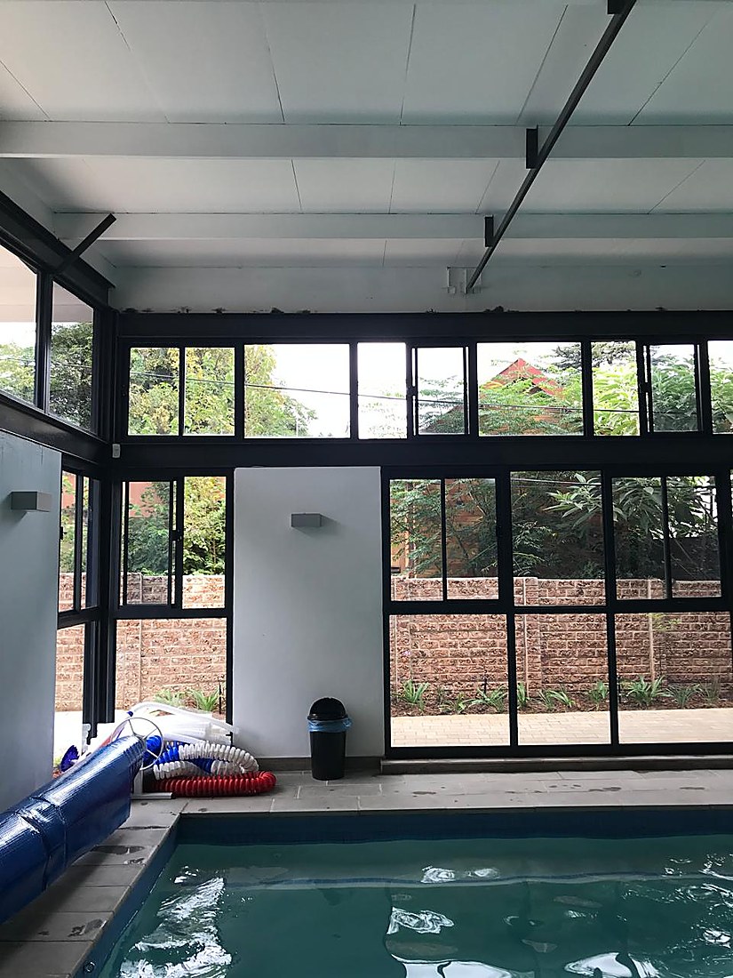 Indoor pool with large windows overlooking the garden and boundary wall